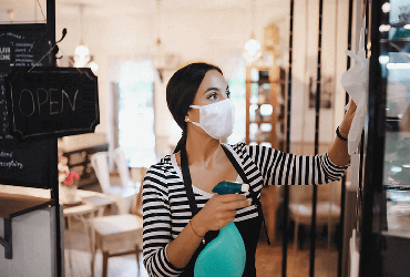 image of a woman sterilizing her place of business to protect against Covid-19 and other sickness.